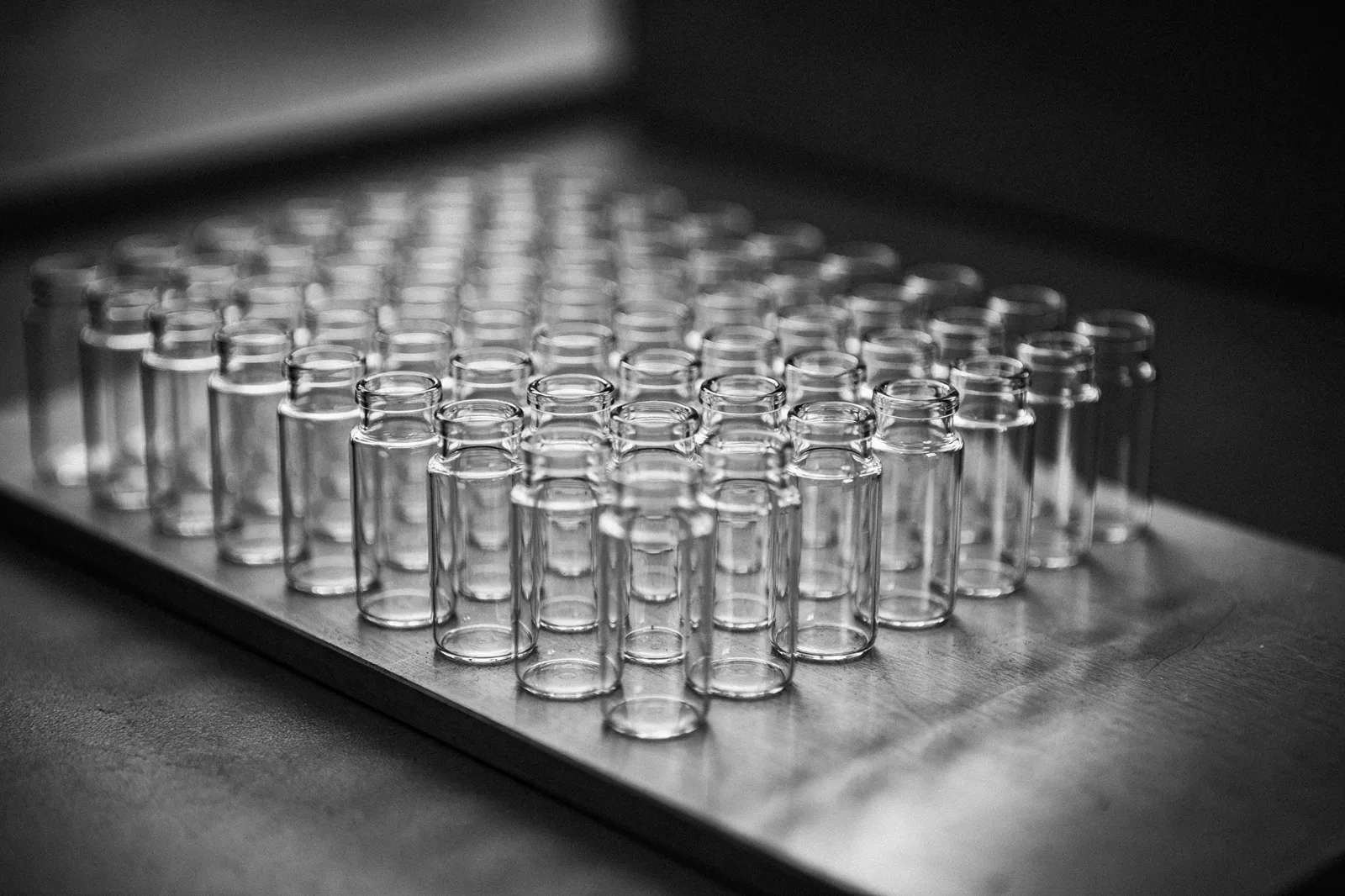 Rows of small glass vials in a laboratory autosampler tray, in black and white